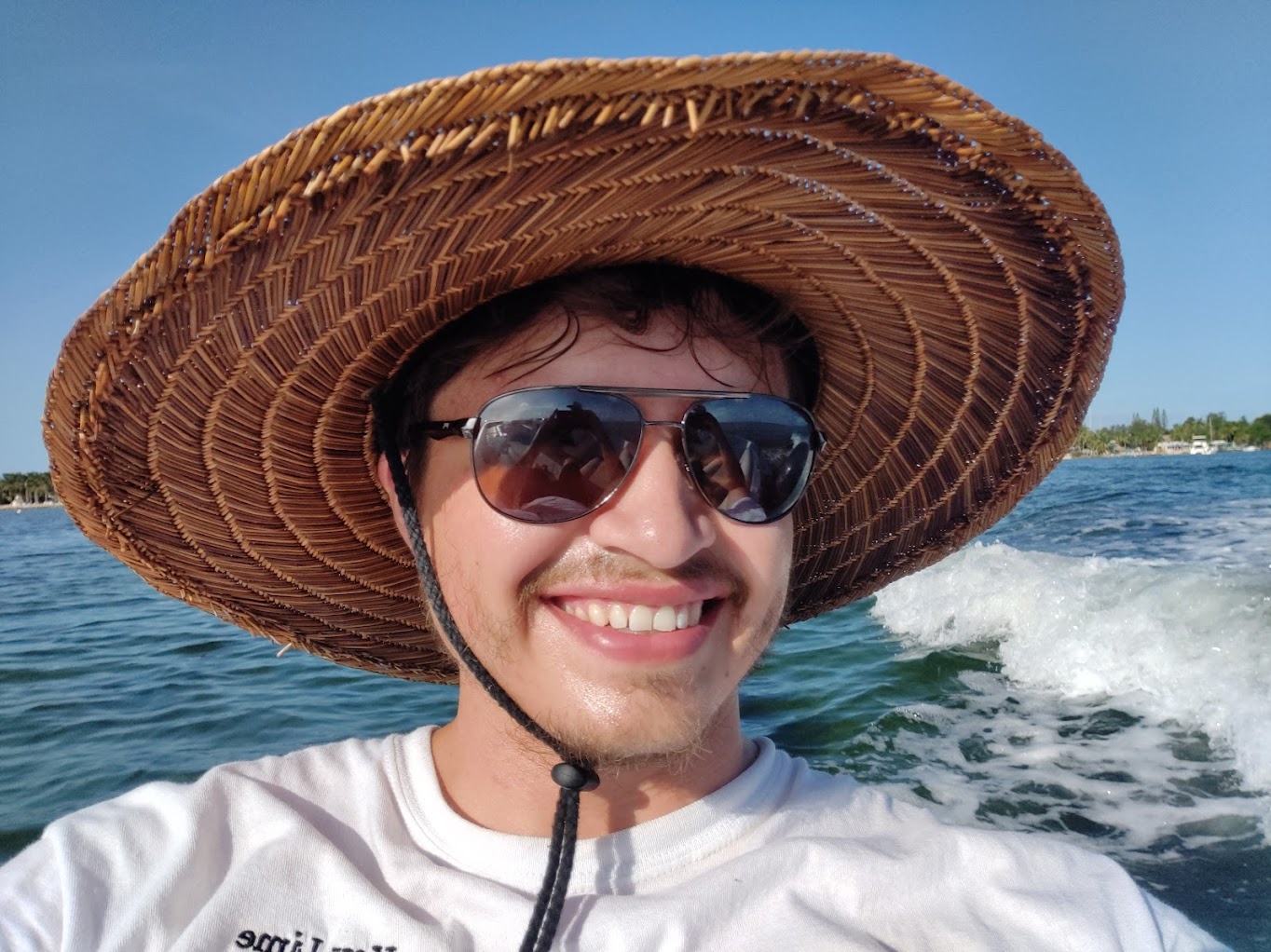 Noah on a skiff in Florida, with a straw hat and sunglasses on